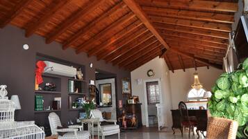 A spacious living room with a high wooden ceiling, a fireplace, and a dining area with a chandelier.