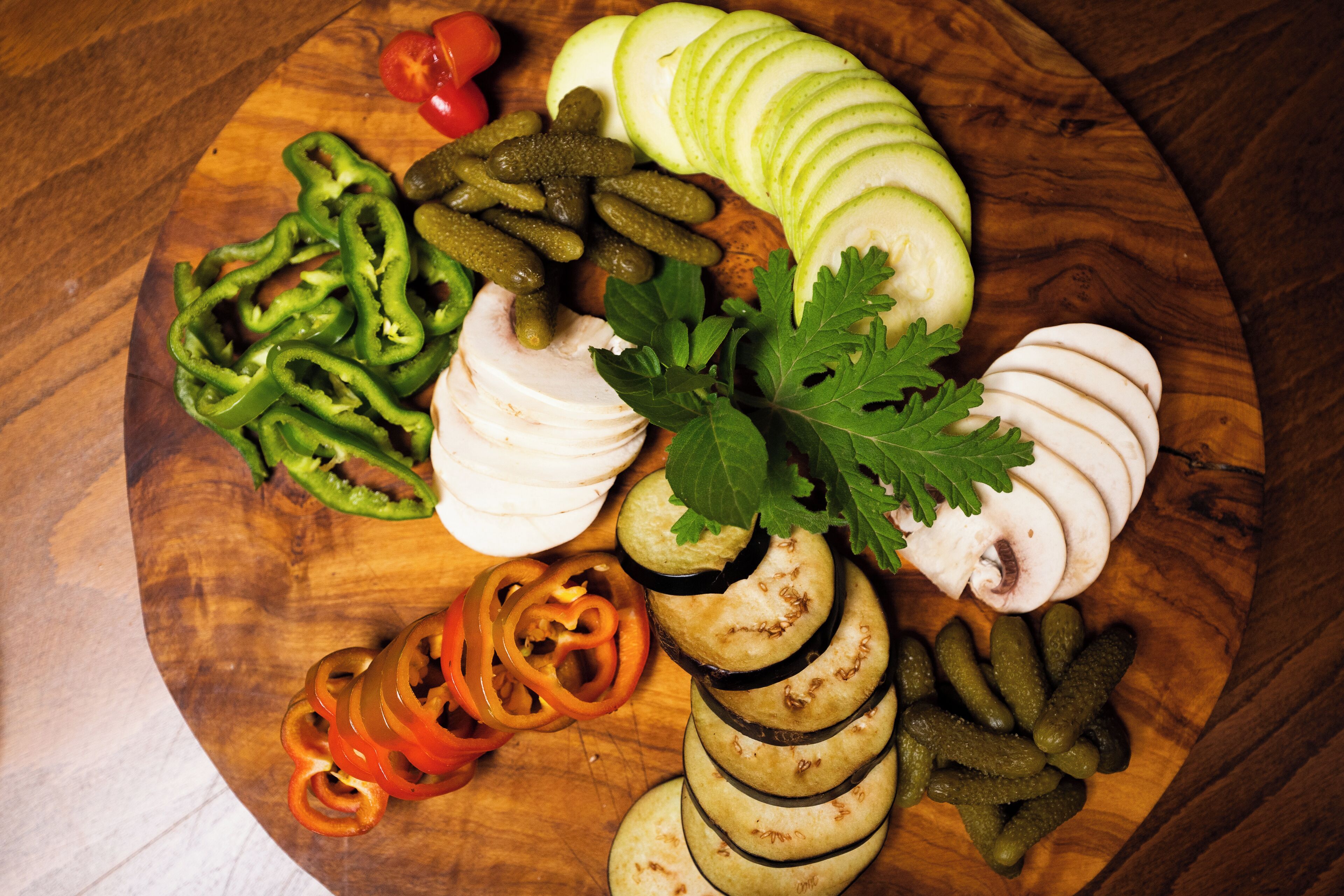 A wooden board with sliced vegetables and herbs.
