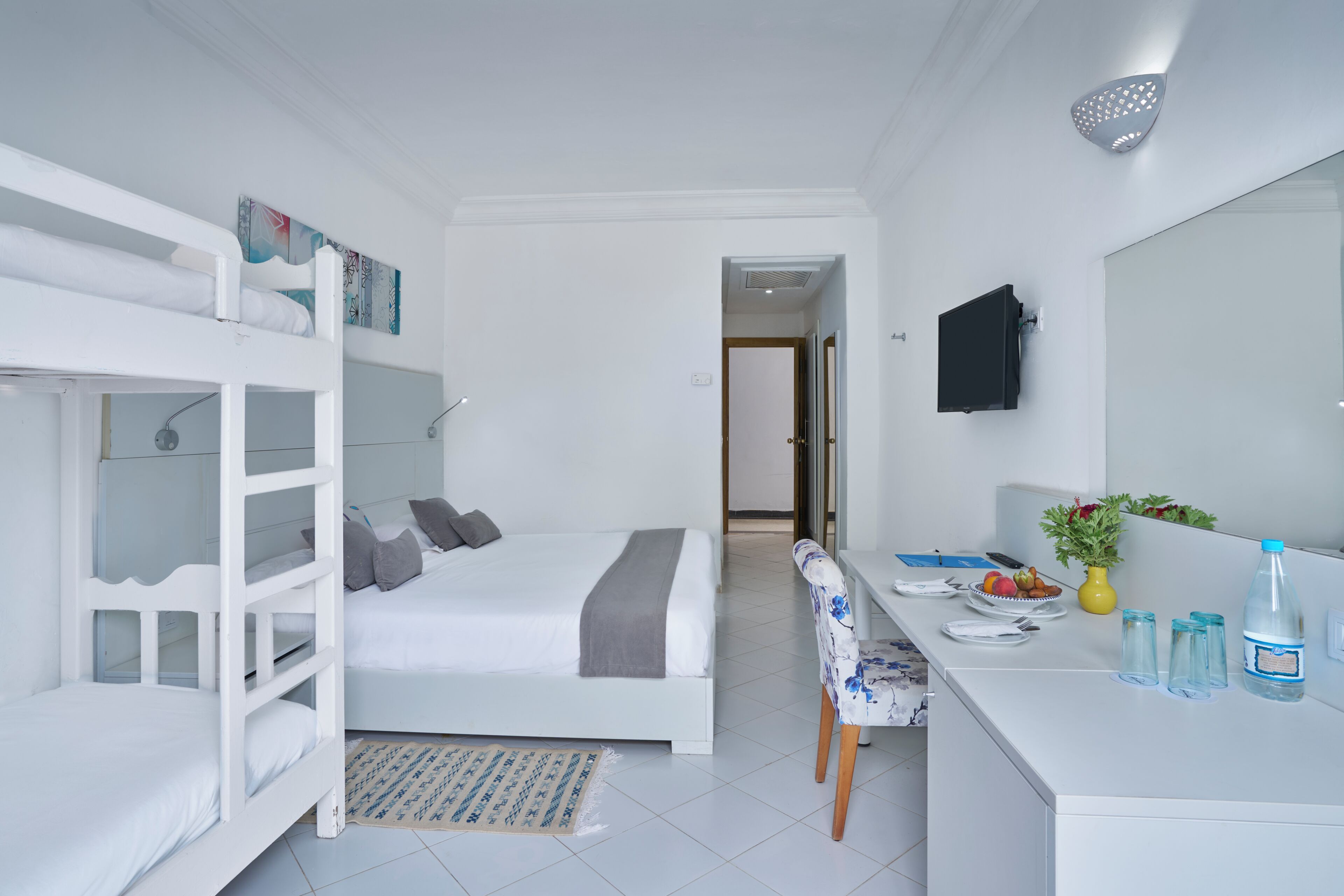 Una habitación con una cama litera, un escritorio con silla, un espejo y una planta pequeña.