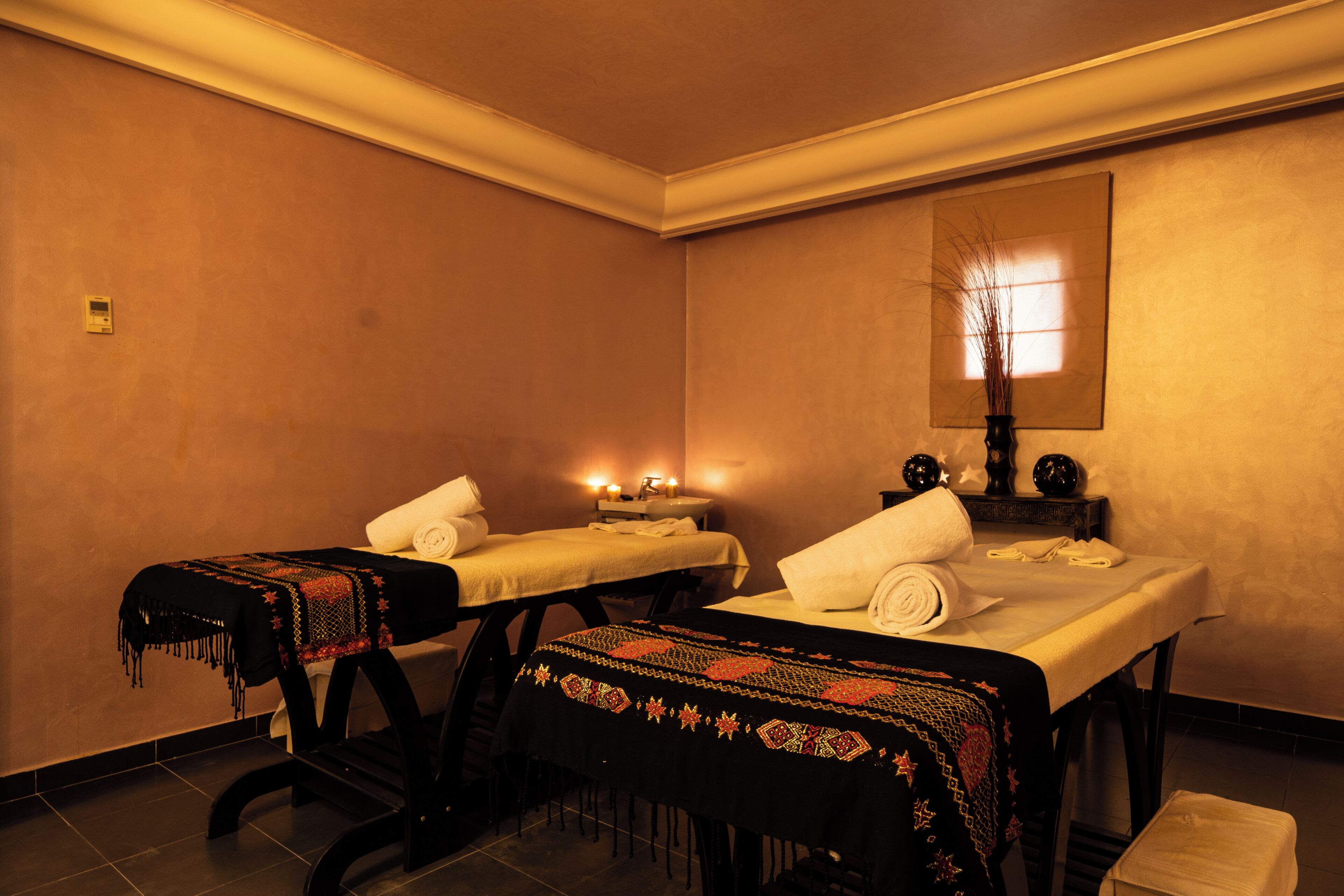 Un cuarto de spa con dos camillas de masaje, cada una con una toalla y un mantel decorativo.