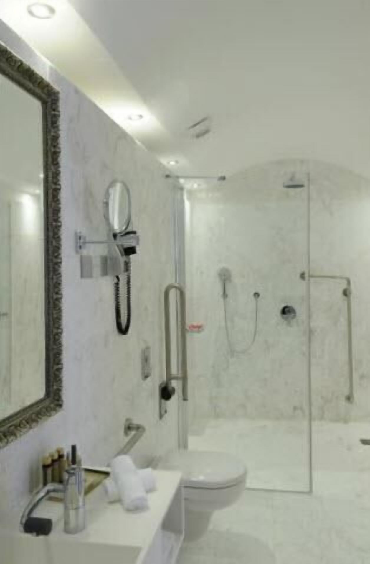 A modern bathroom with a glass-enclosed shower, a large mirror, and a white sink.