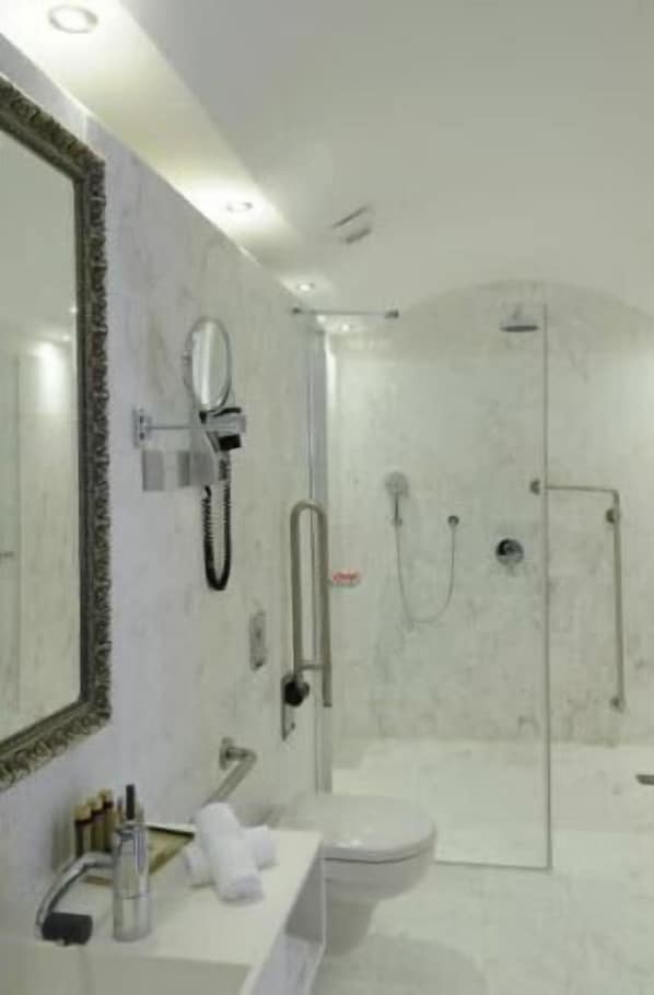 A modern bathroom with a glass-enclosed shower, a large mirror, and a white sink.