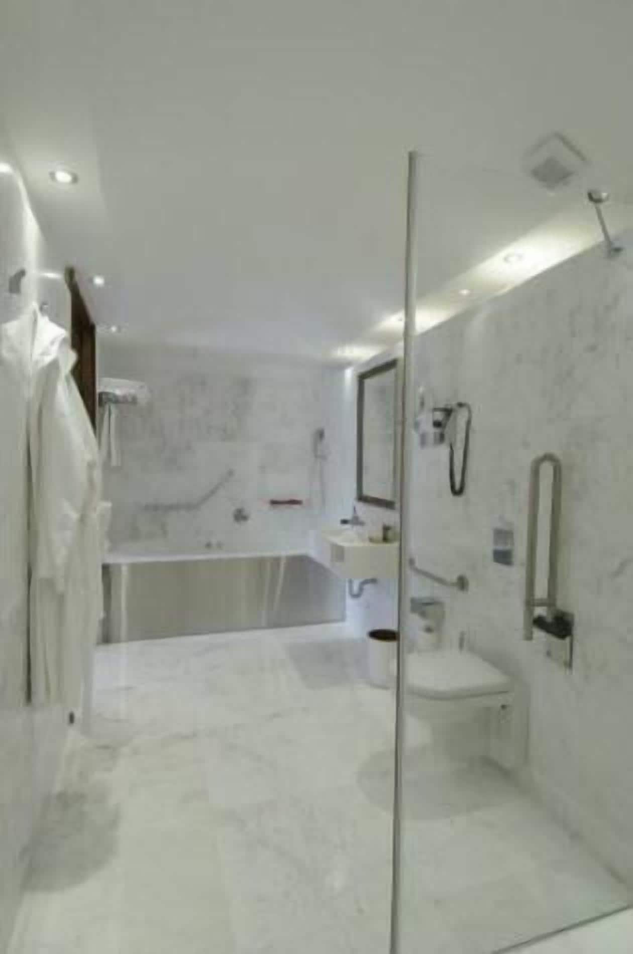 A modern bathroom with a glass shower enclosure, a bathtub, and a vanity with a mirror.