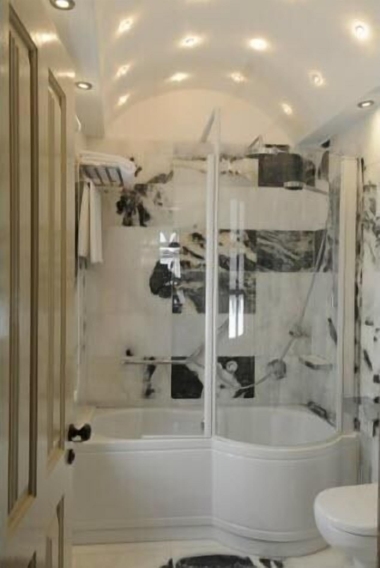 A modern bathroom with a glass-enclosed shower, a white bathtub, and a toilet.