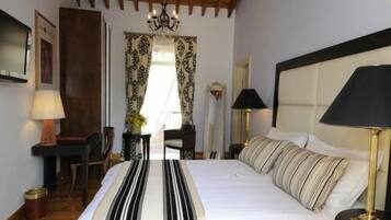 Una habitación de hotel con una cama grande, un escritorio, una silla, una lámpara y una ventana con cortinas.