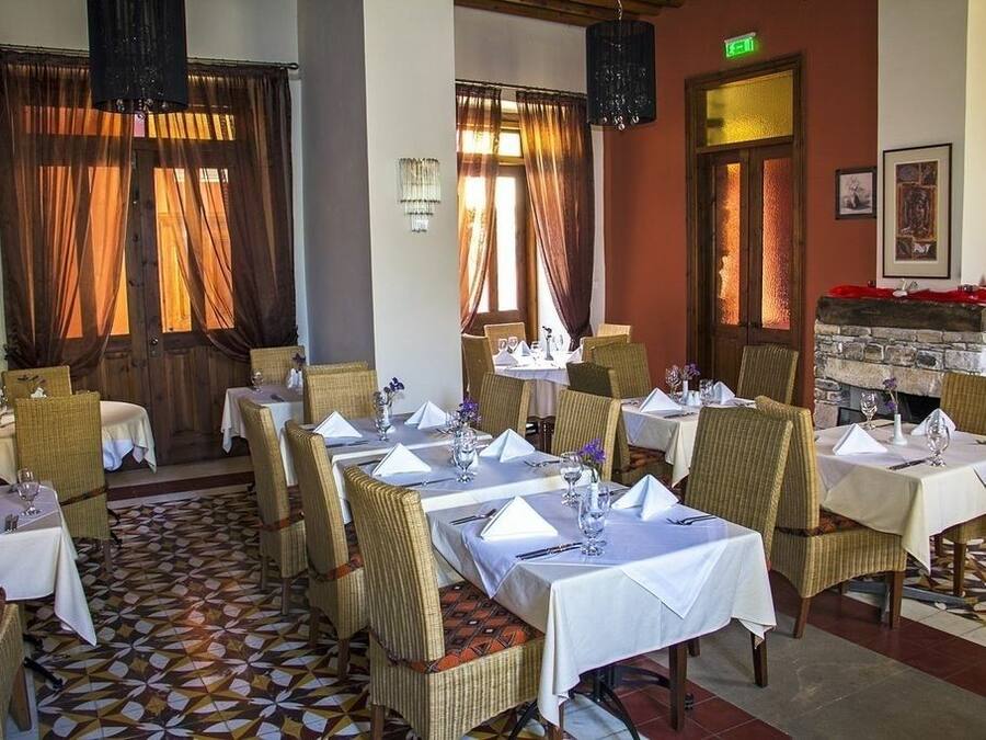 Un comedor con mesas dispuestas para el servicio, sillas de mimbre y suelo con diseño.