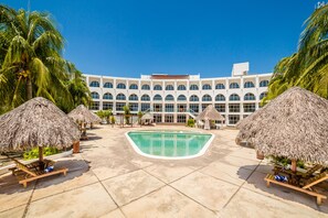 A resort with a central pool, thatched umbrellas, and a large building with multiple windows. - Uxmal Resort Maya (Muna)