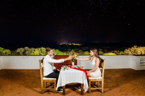 A couple toasting at a table with a view of the night sky and distant landscape. - Uxmal Resort Maya (Muna)