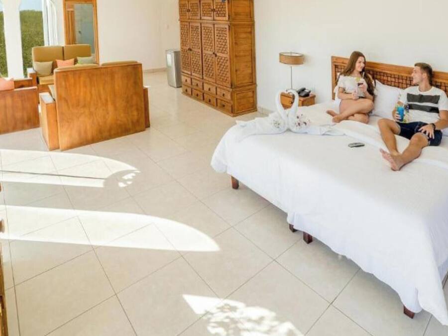 Una habitación de hotel con una cama grande, un armario de madera, un escritorio y una silla.