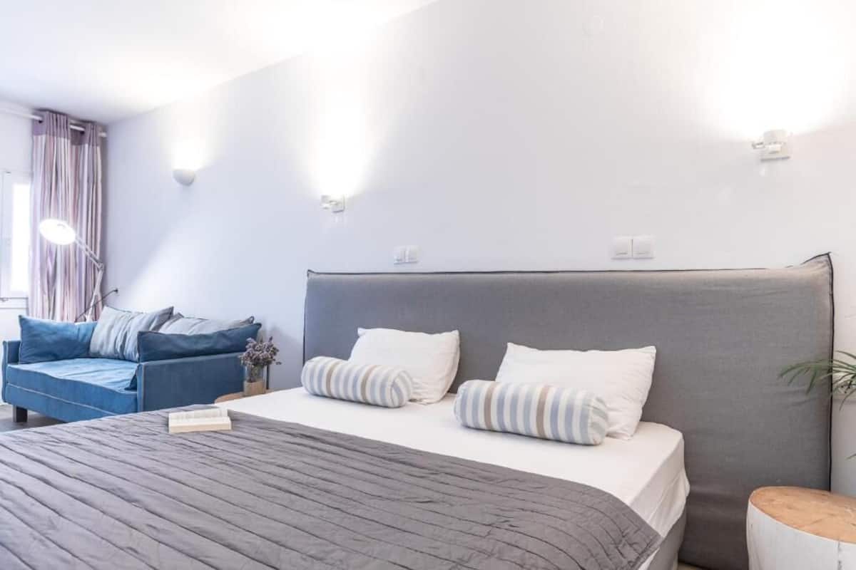 A modern bedroom with a large bed, a blue sofa, and a bedside table.