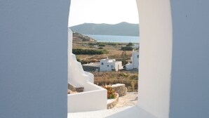 A view through a white archway overlooking a coastal village with white buildings and a body of water. - Anamar Mykonos Natural Retreat (Mykonos)