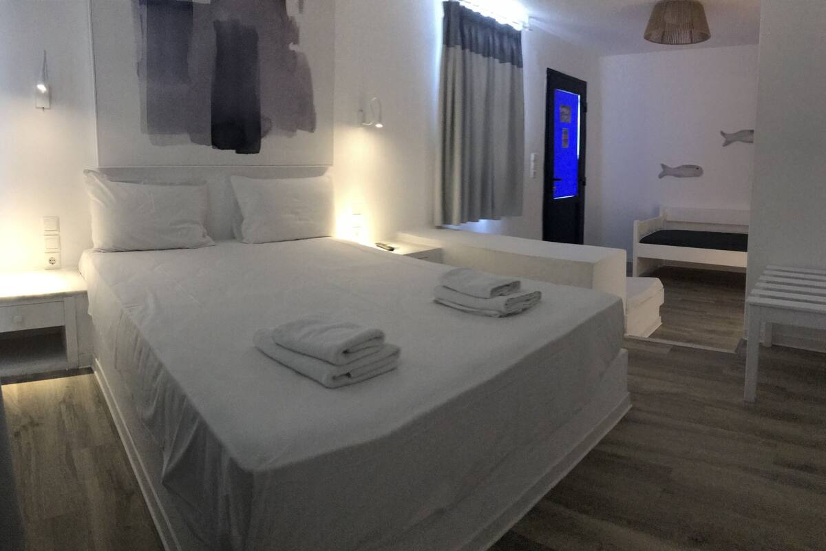 A modern bedroom with a large bed, bedside tables, a bench, and a fish decoration on the wall.