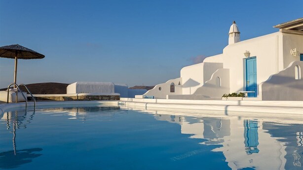 A swimming pool with a clear blue water surface, a blue door, and white buildings with unique architectural features. - Anamar Mykonos Natural Retreat (Mykonos)