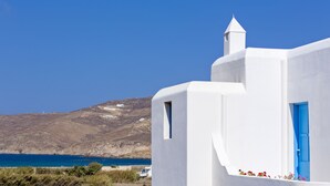 A white building with a blue door, a small window, and a chimney. - Anamar Mykonos Natural Retreat (Mykonos)