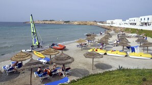 Una playa con tumbonas, sombrillas y barcos.
