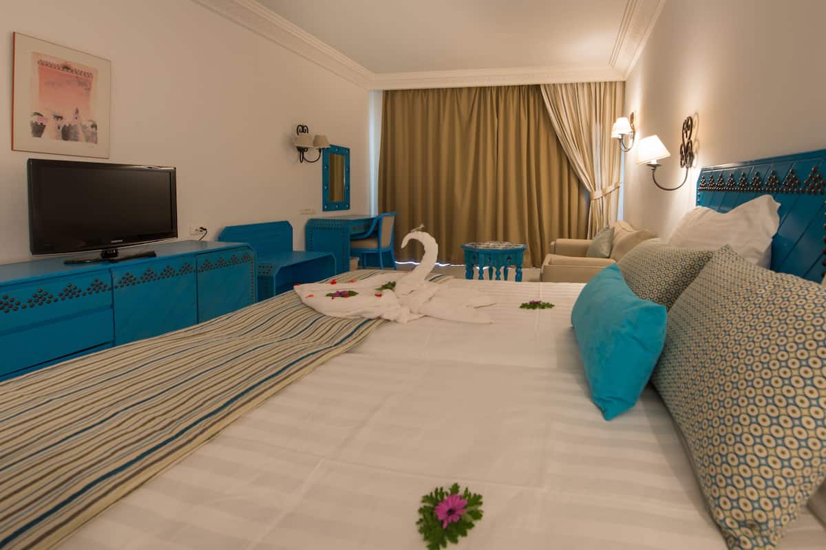 Una habitación de hotel con cama, televisor, escritorio y una silla.