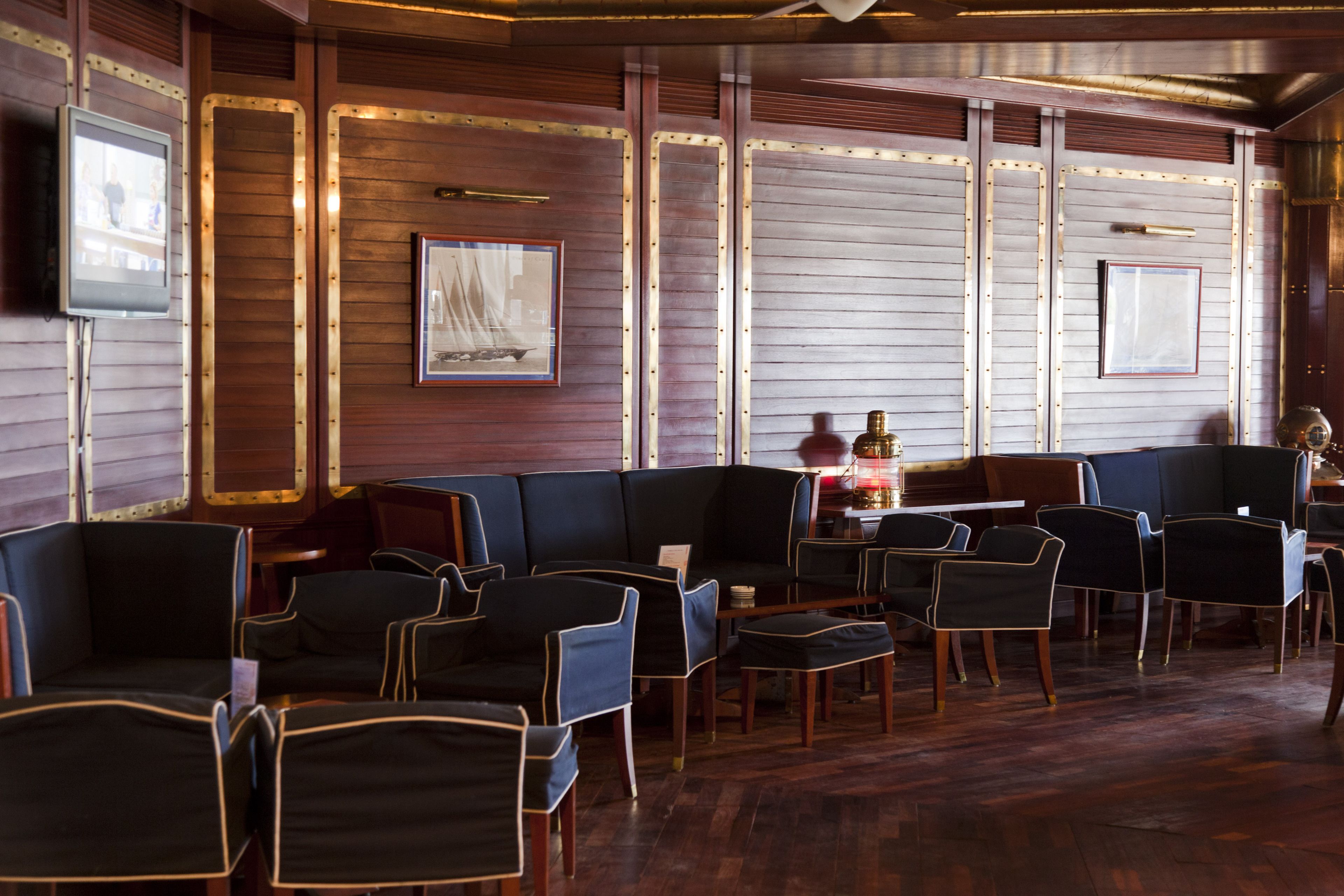 Um restaurante com painéis de madeira, assentos estofados em preto e obras de arte emolduradas nas paredes.