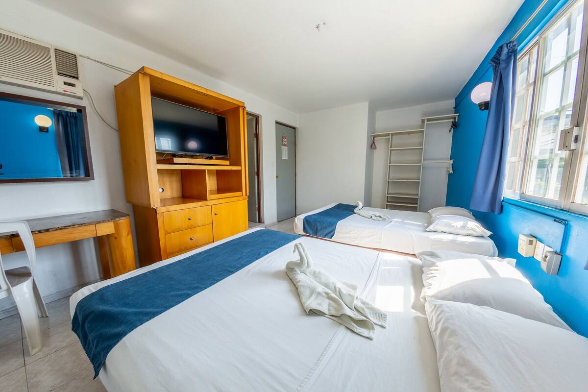 A hotel room with two beds, a desk, a television, and a wardrobe.