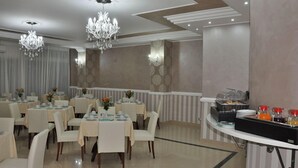 A dining area with tables set for service, a buffet station with food and beverages, and decorative lighting. - Hotel Inn (Taormina)