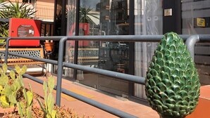 A building with a balcony, a red fire alarm box, and a green decorative object. - Hotel Inn (Taormina)