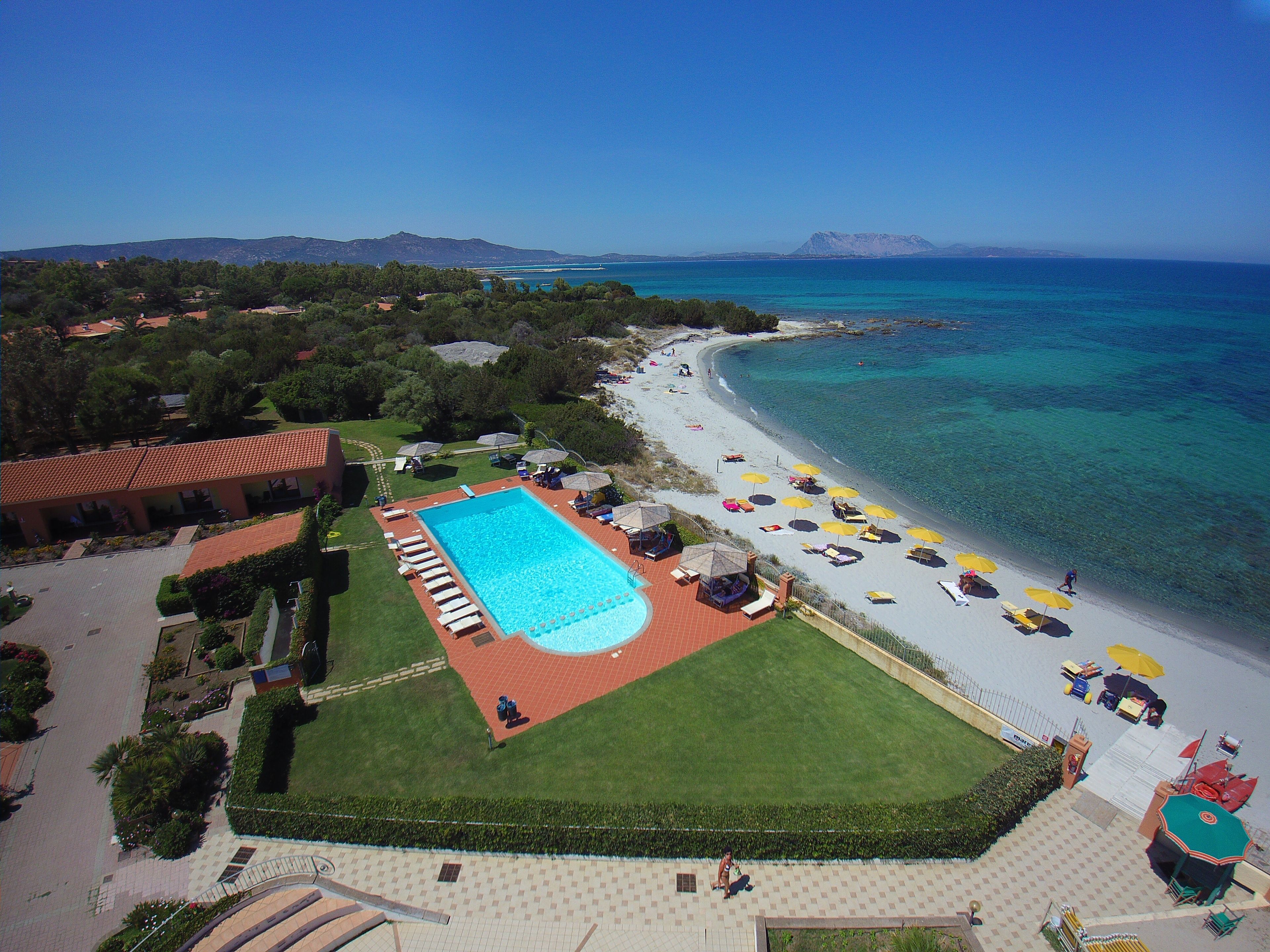 A resort with a swimming pool, beach, and ocean view.