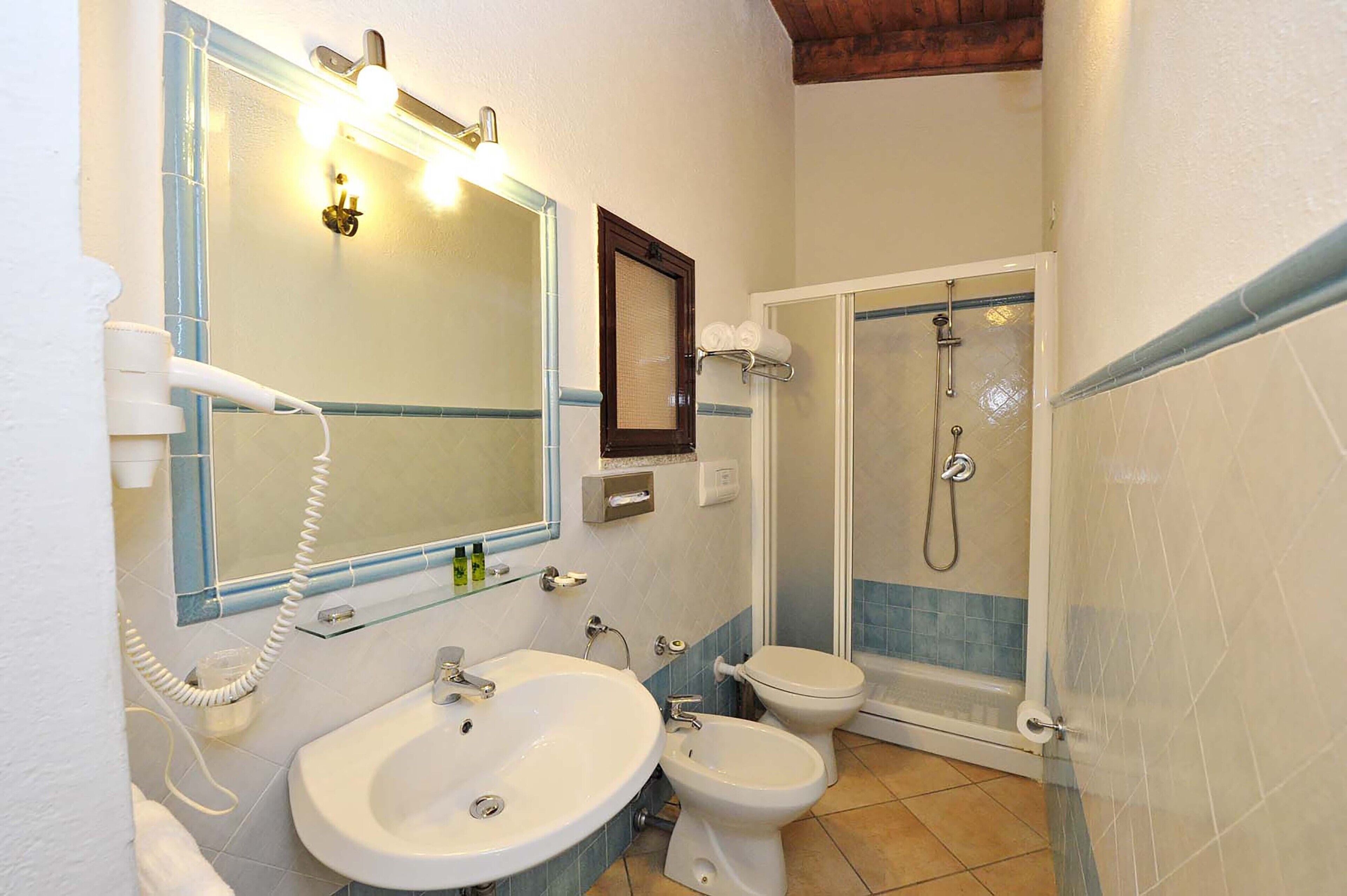 Un baño con lavamanos, dos inodoros, ducha y secador de pelo.