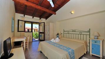 Ein Schlafzimmer mit Bett, Schreibtisch, Stuhl, Kleiderschrank und Deckenventilator.