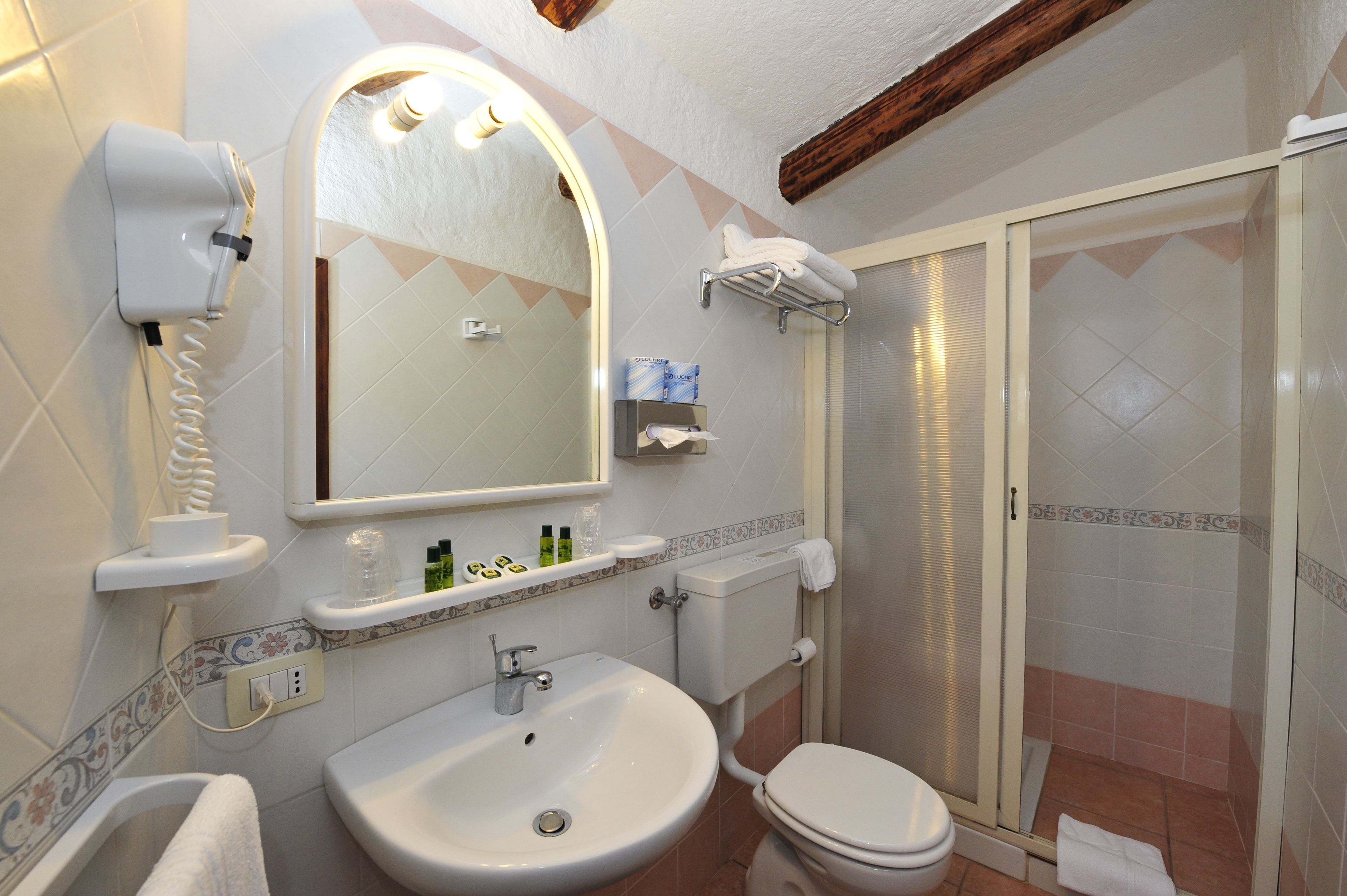 A bathroom with a sink, toilet, and a glass-enclosed shower.