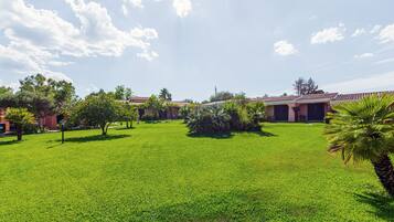A well-maintained grassy courtyard with a building featuring a red-tiled roof and a palm tree.