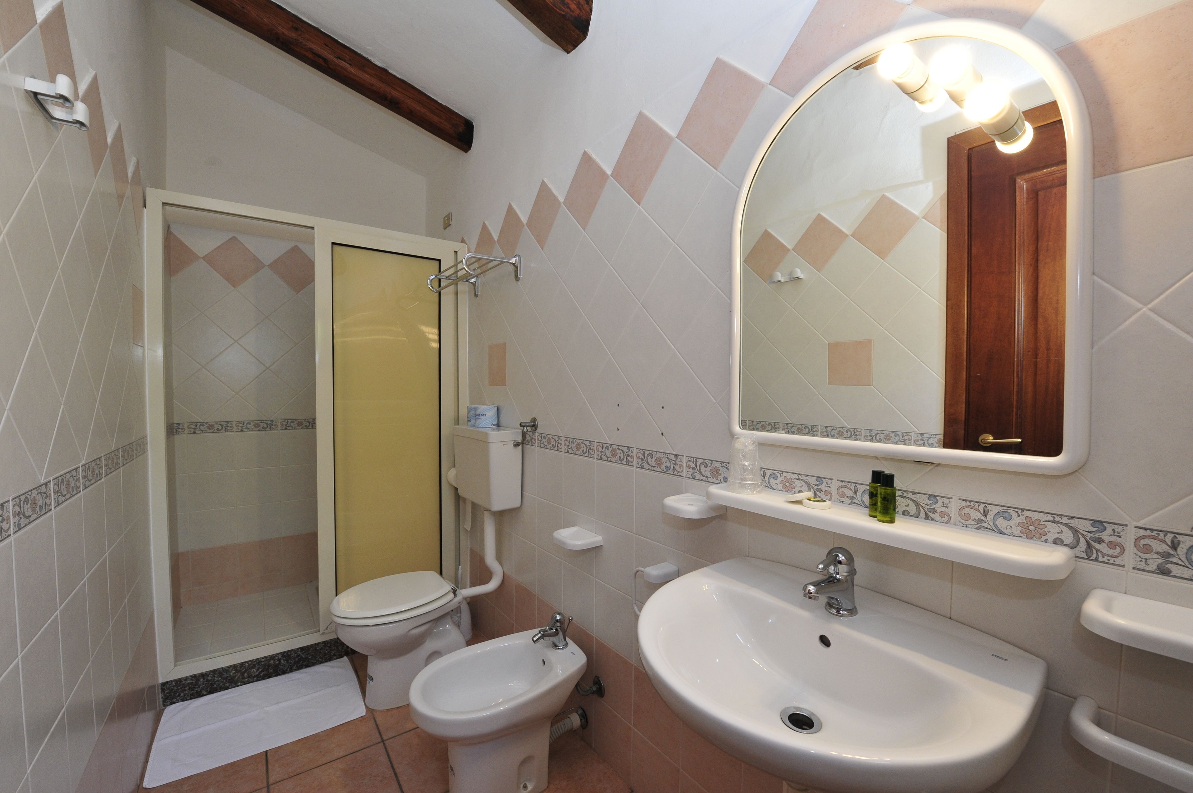 Une salle de bain comprenant des toilettes, un bidet, un lavabo et un espace douche.