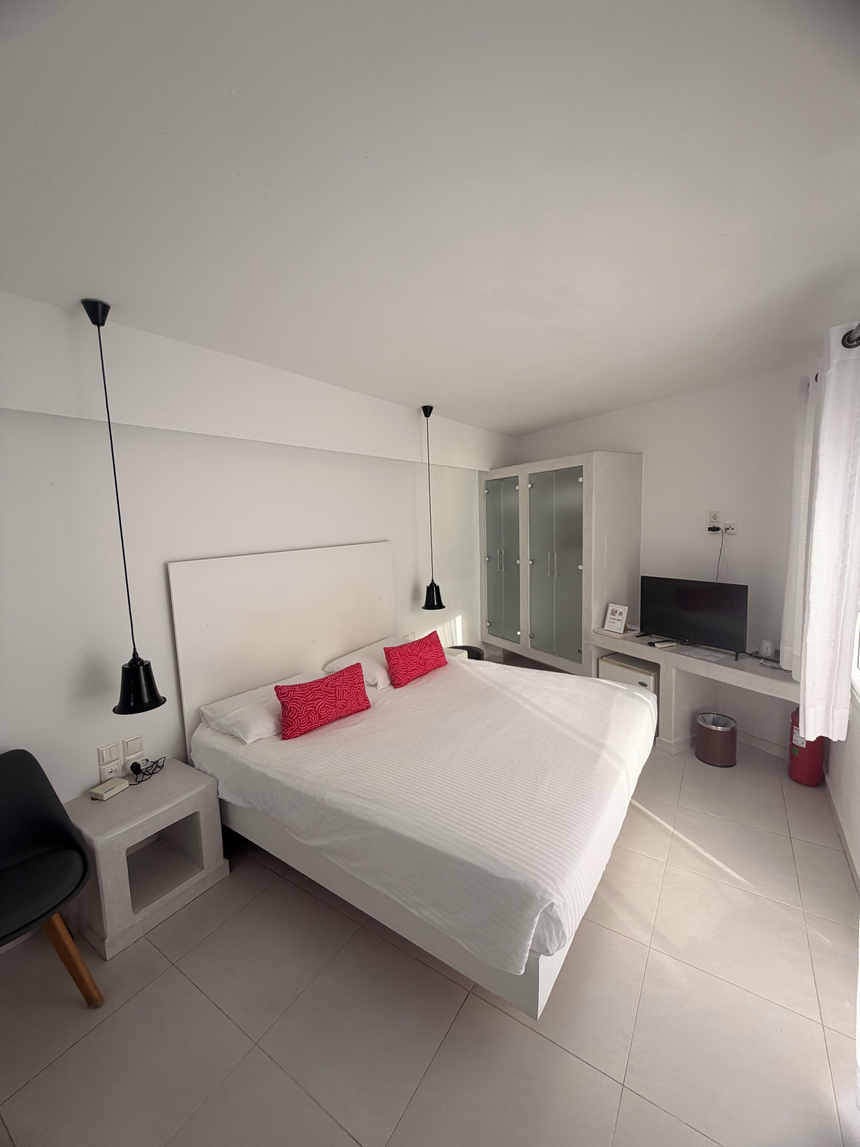 Une chambre d’hôtel moderne avec un grand lit, un bureau avec une télévision et une armoire.