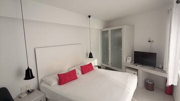 Une chambre d’hôtel moderne avec un grand lit, un bureau avec une télévision et une armoire.