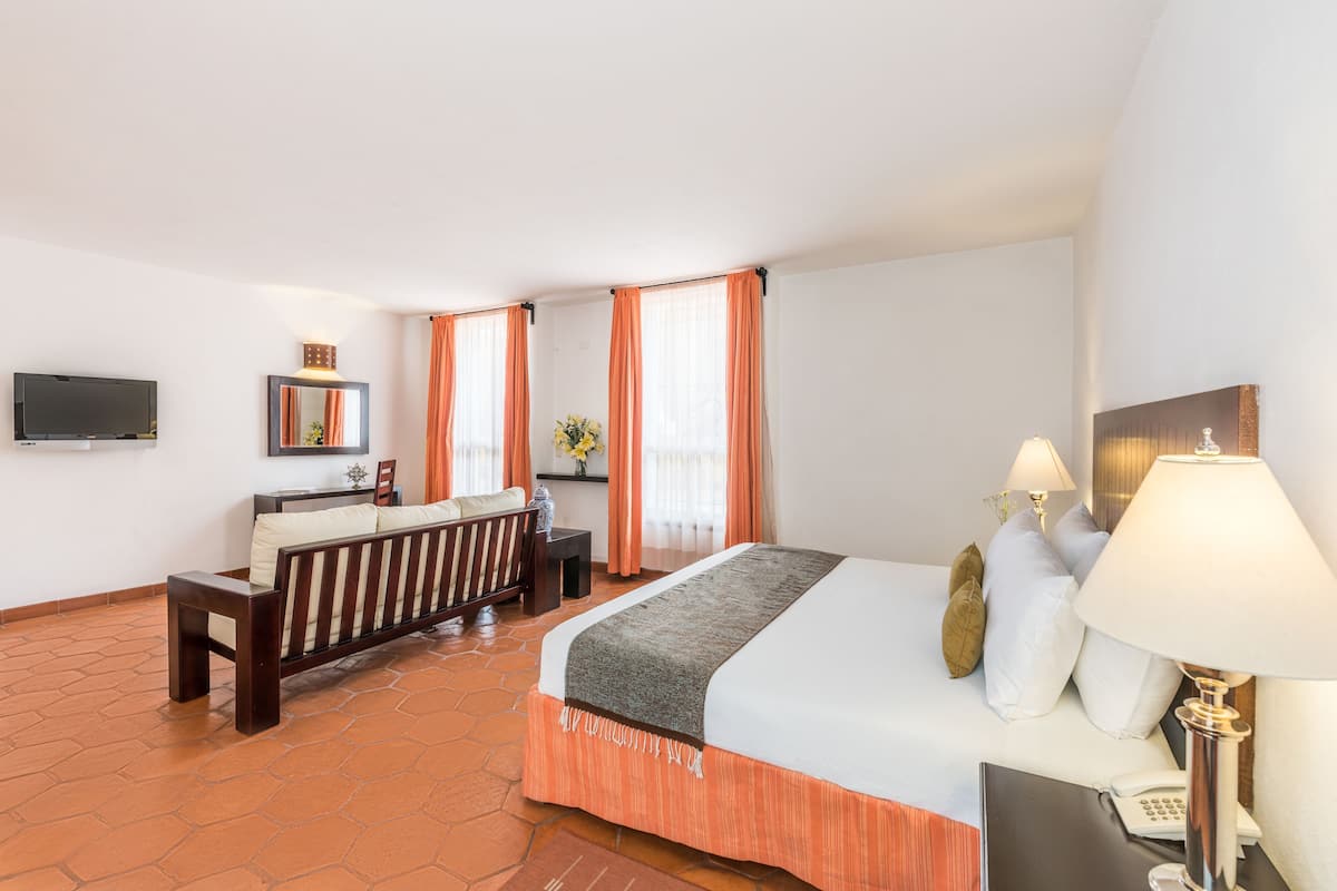 Une chambre d’hôtel avec un lit, un bureau, une télévision et une fenêtre avec des rideaux.