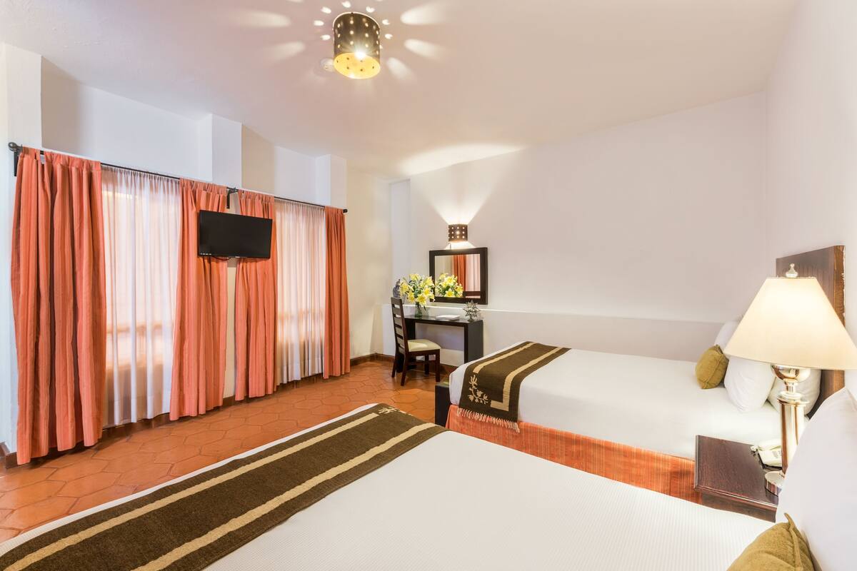 Une chambre d’hôtel avec deux lits, un bureau, une télévision et une lampe de bureau.