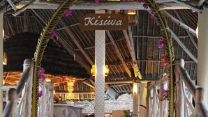 Un espacio al aire libre cubierto con un letrero que dice "Kisiva", barandas de madera y una escalera que lleva a una piscina.