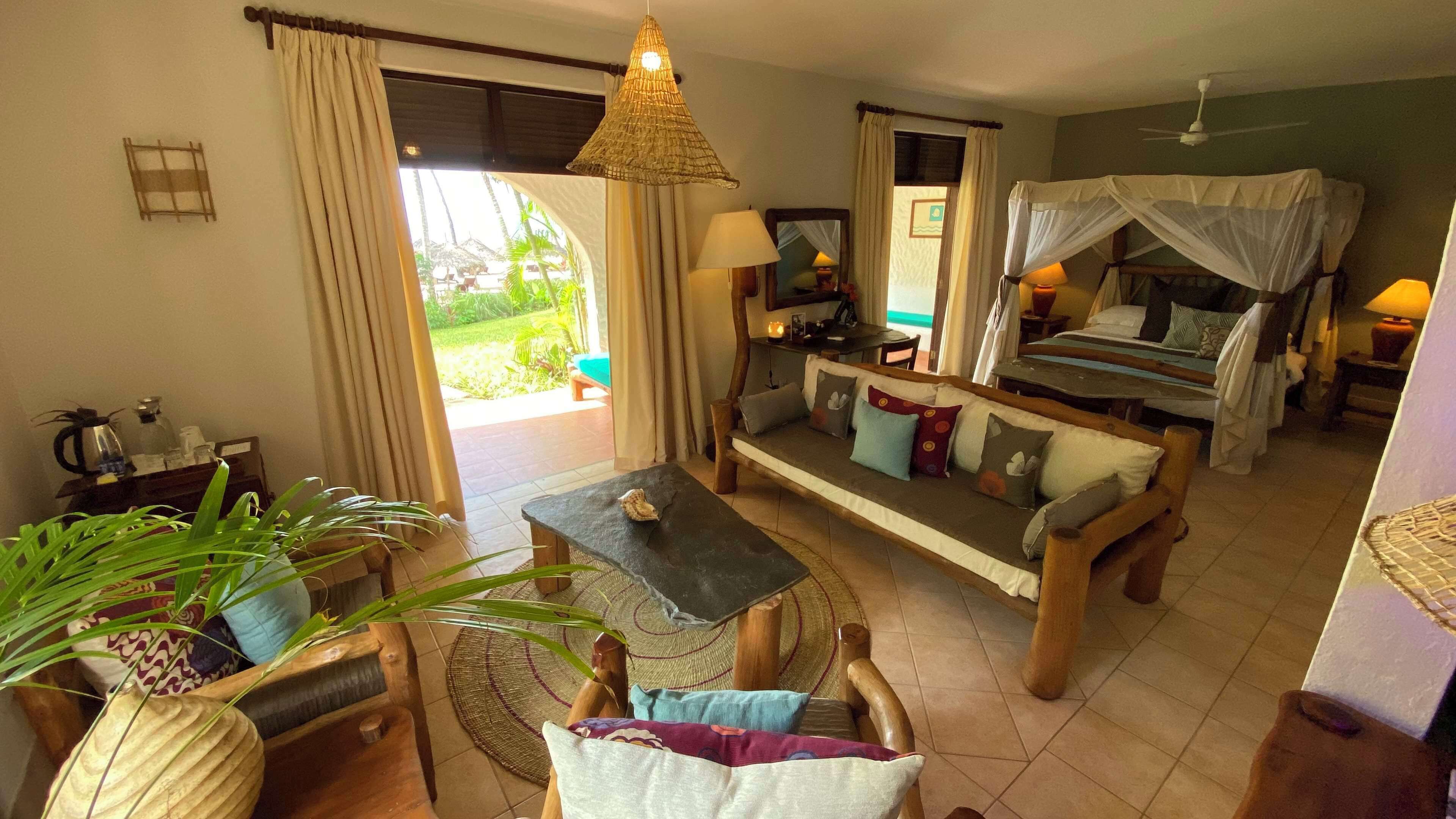 Una habitación acogedora con sofá, mesa, lámpara colgante y cama con dosel.