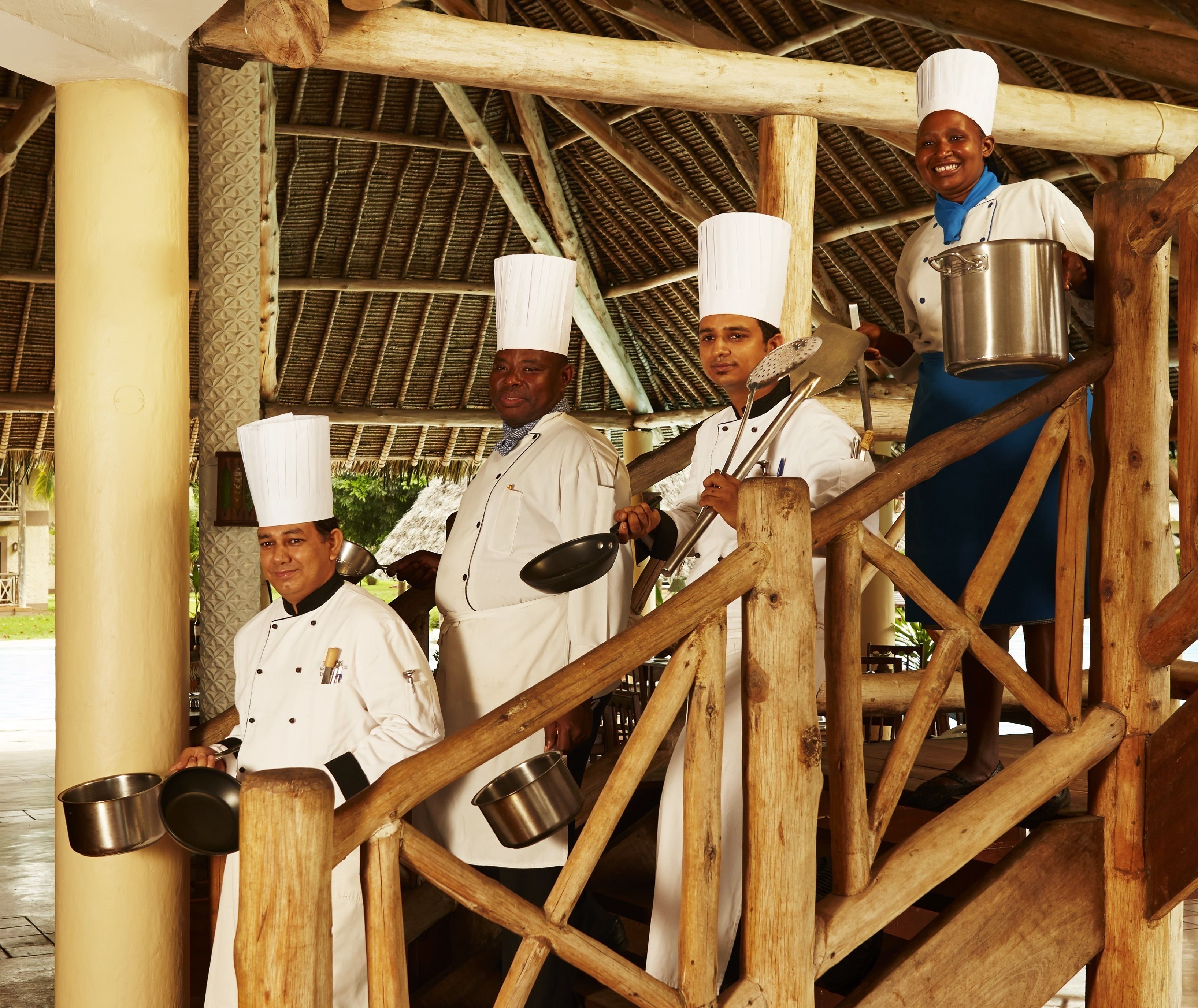 A group of chefs in white uniforms and hats standing on a wooden staircase.