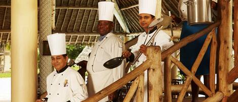 A group of chefs in white uniforms and hats standing on a wooden staircase.