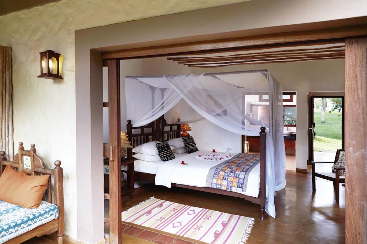 A bedroom with a four-poster bed, a wooden headboard, and a white canopy.