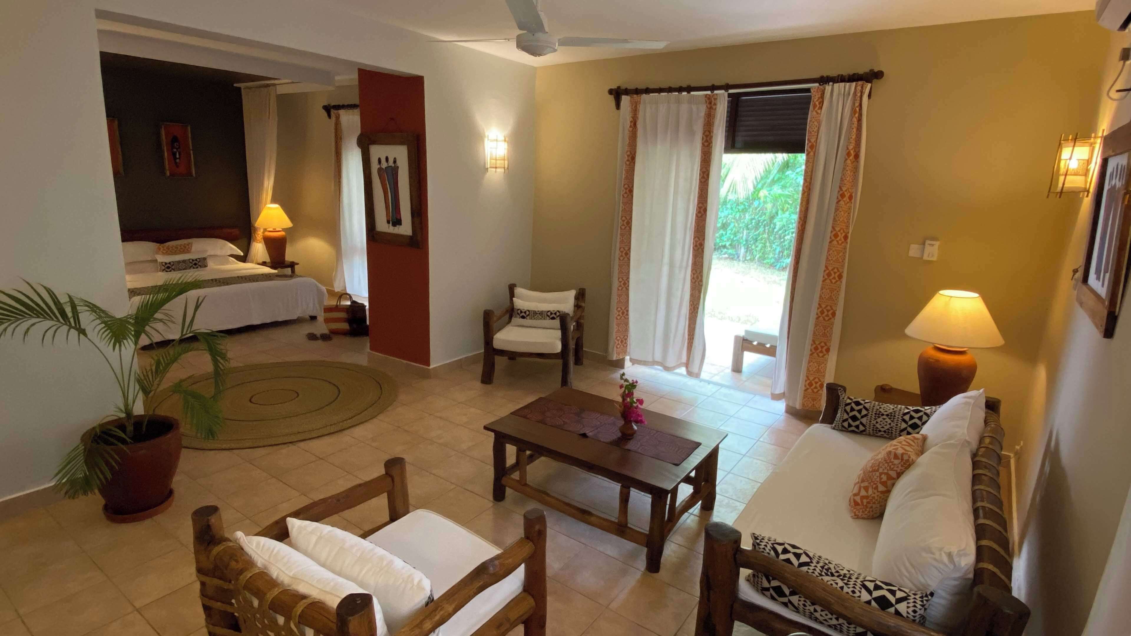Una habitación de hotel con una cama, un sofá, una silla, una mesa y una planta en maceta.