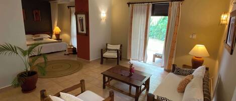 Una habitación de hotel con una cama, un sofá, una silla, una mesa y una planta en maceta.