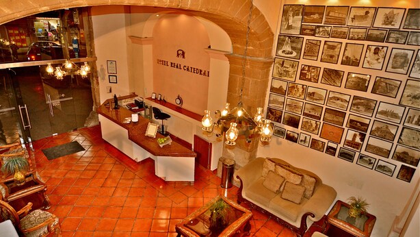 Una hall d'albergo con scrivania della reception, area salotto e una parete di fotografie.