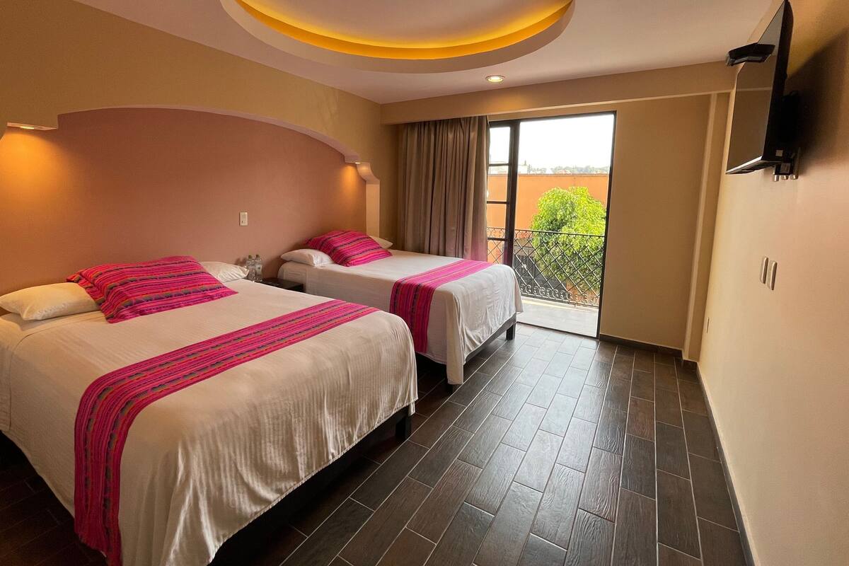 A hotel room with two beds, a TV, and a balcony with a view.