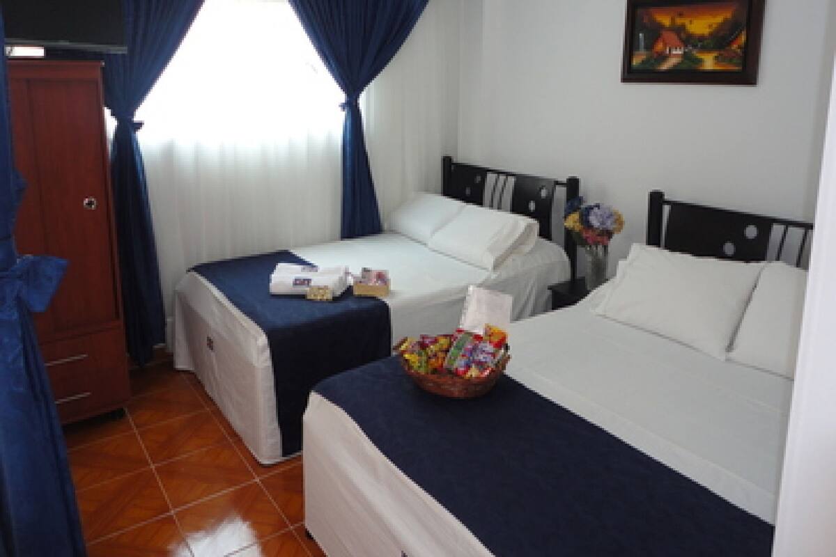Una habitación de hotel con dos camas, un armario de madera, un cuadro en la pared y una ventana con cortinas.