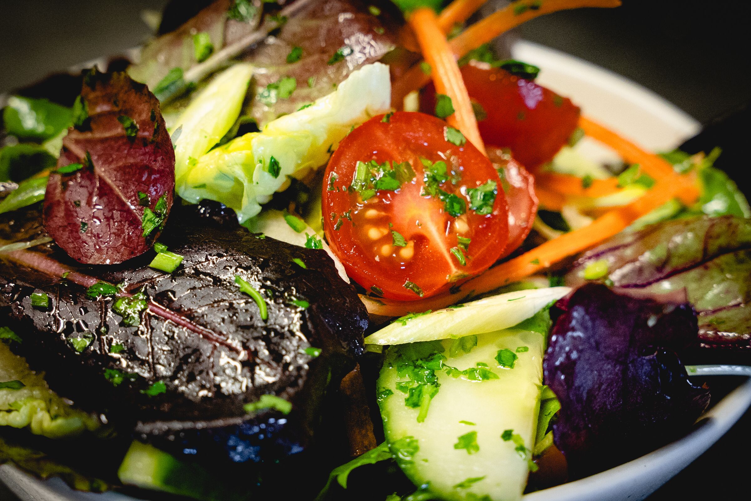 Primer plano de una ensalada con varias verduras y un trozo de carne.