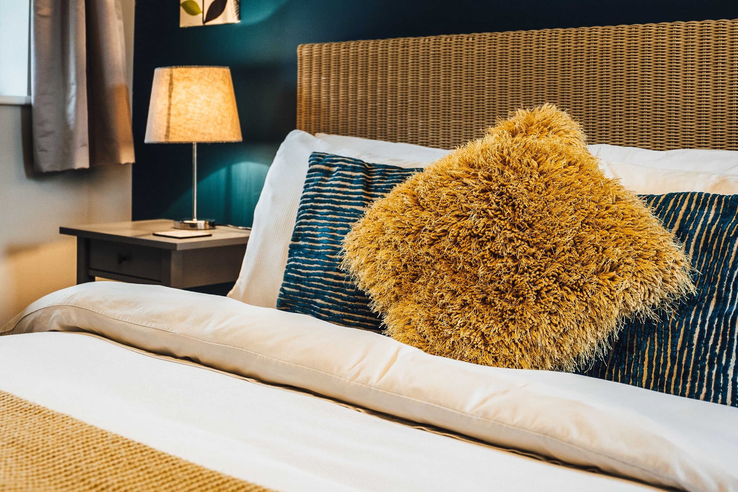 Un lit bien fait, avec une couette blanche et plusieurs oreillers, dont un grand oreiller moelleux.