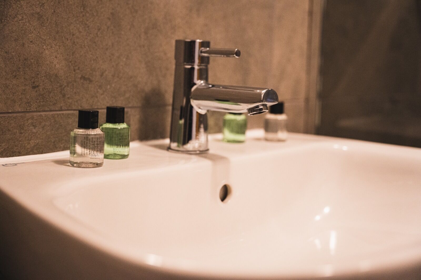 A bathroom sink with a chrome faucet and two bottles of liquid soap.