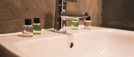 Un lavabo de salle de bain avec un robinet chromé et deux flacons de savon liquide.