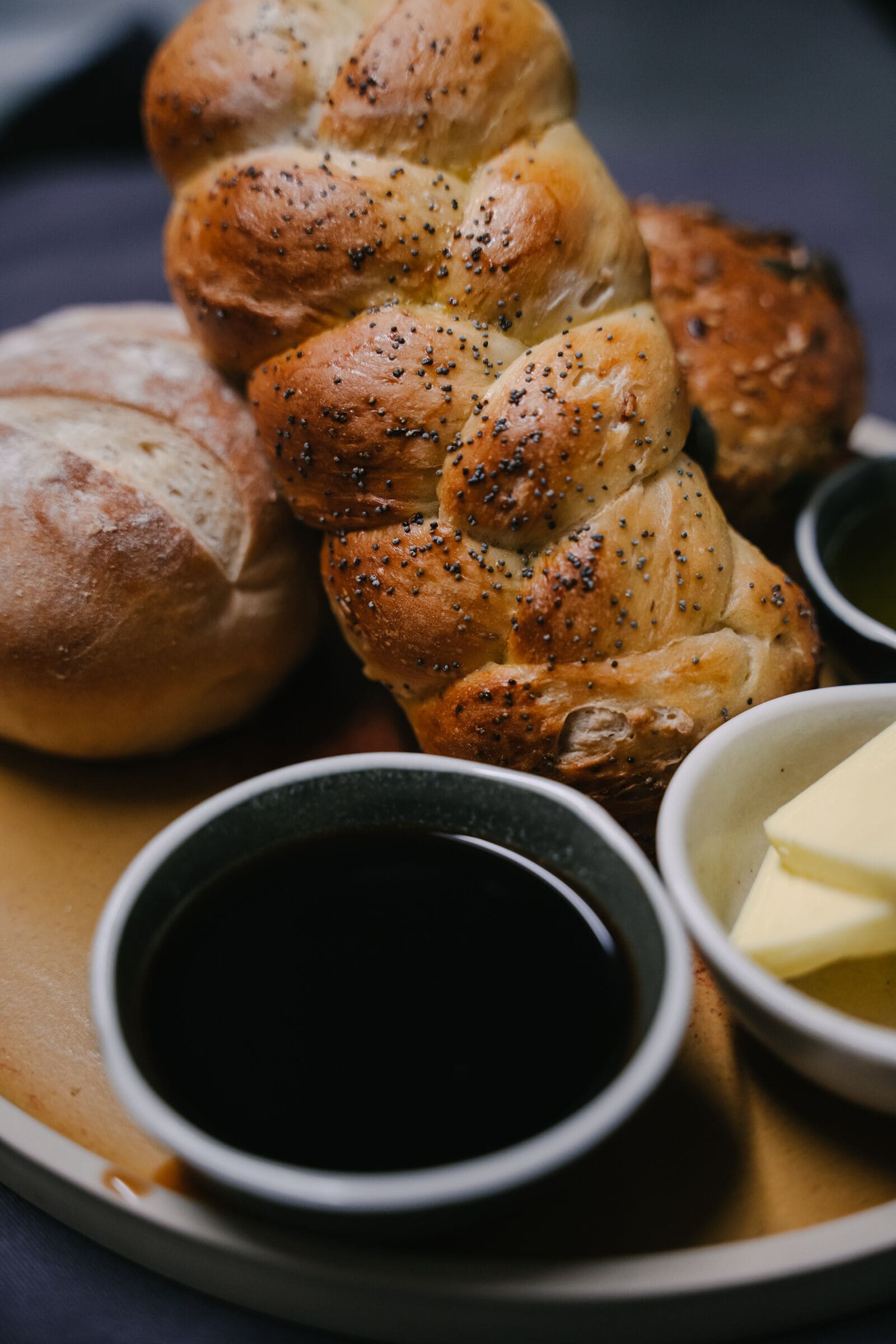 A loaf of bread with poppy seeds and a bowl of butter.