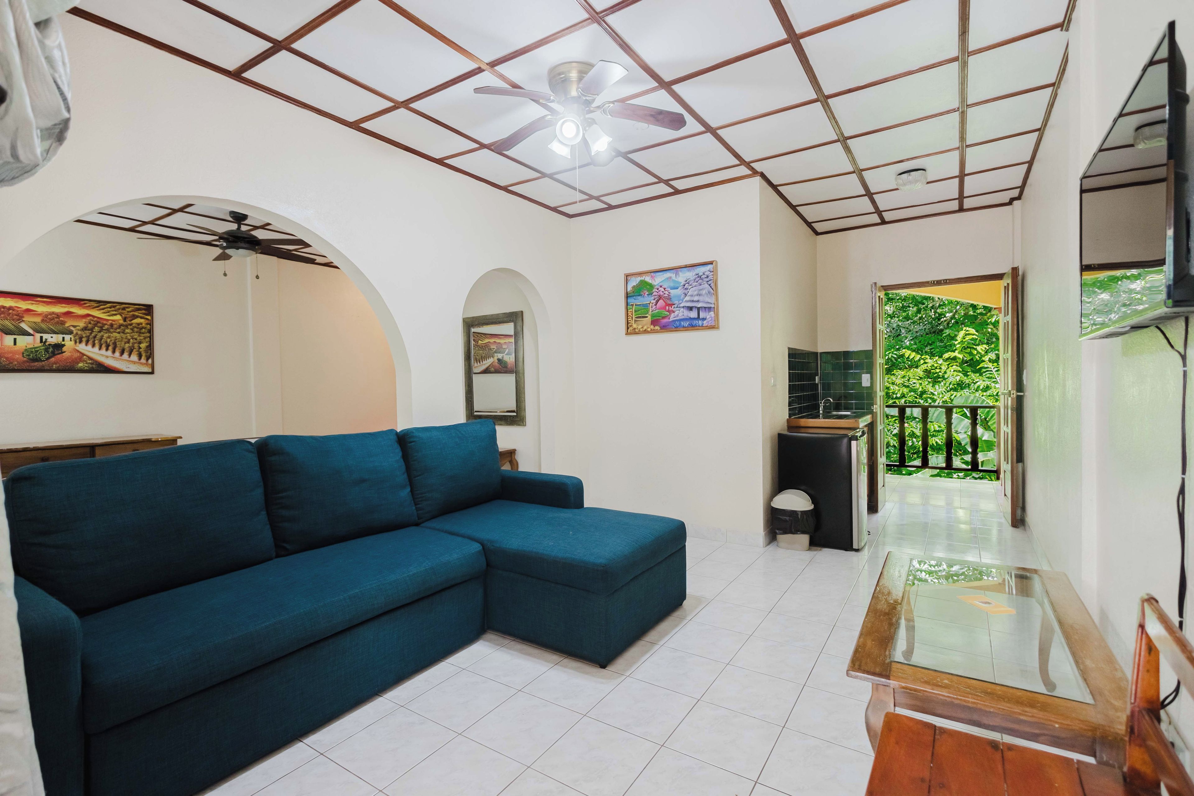 Sala de estar com sofá azul, ventilador de teto e quadro na parede.